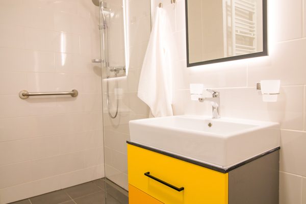 Kupaonica u domu Senior Garden s tušem, rukohvatima i modernim umivaonikom.