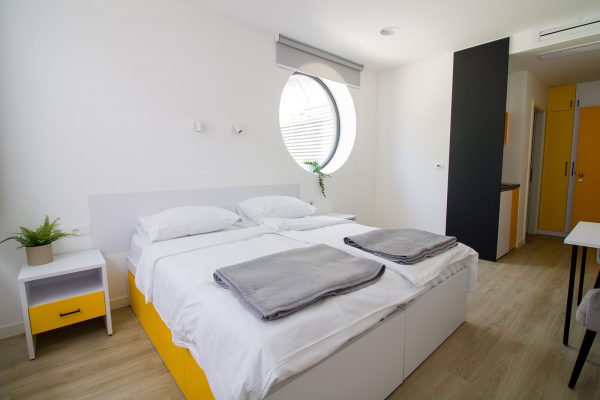 Pogled na bračnu sobu s kuhinjom, stolicama i velikim prozorima