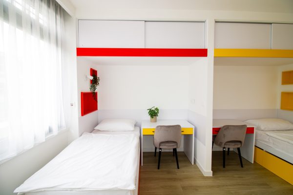 Dvokrevetna soba u domu za starije s modernim namještajem i velikim prozorom