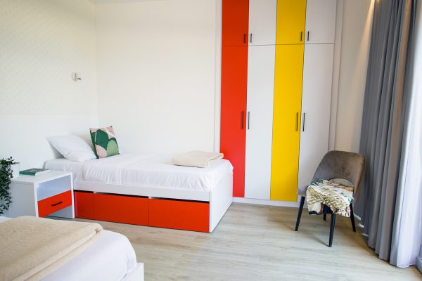 Kreveti s noćnim ormarićima i garderobnim ormarom u spavaćem dijelu apartmana za starije osobe