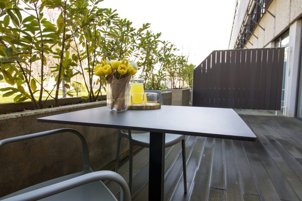 Vanjska terasa sa stolom i ukrasnim biljkama u teglama u domu za starije osobe